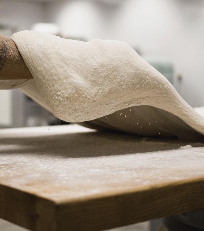 Artigiano che stende l'impasto a mano